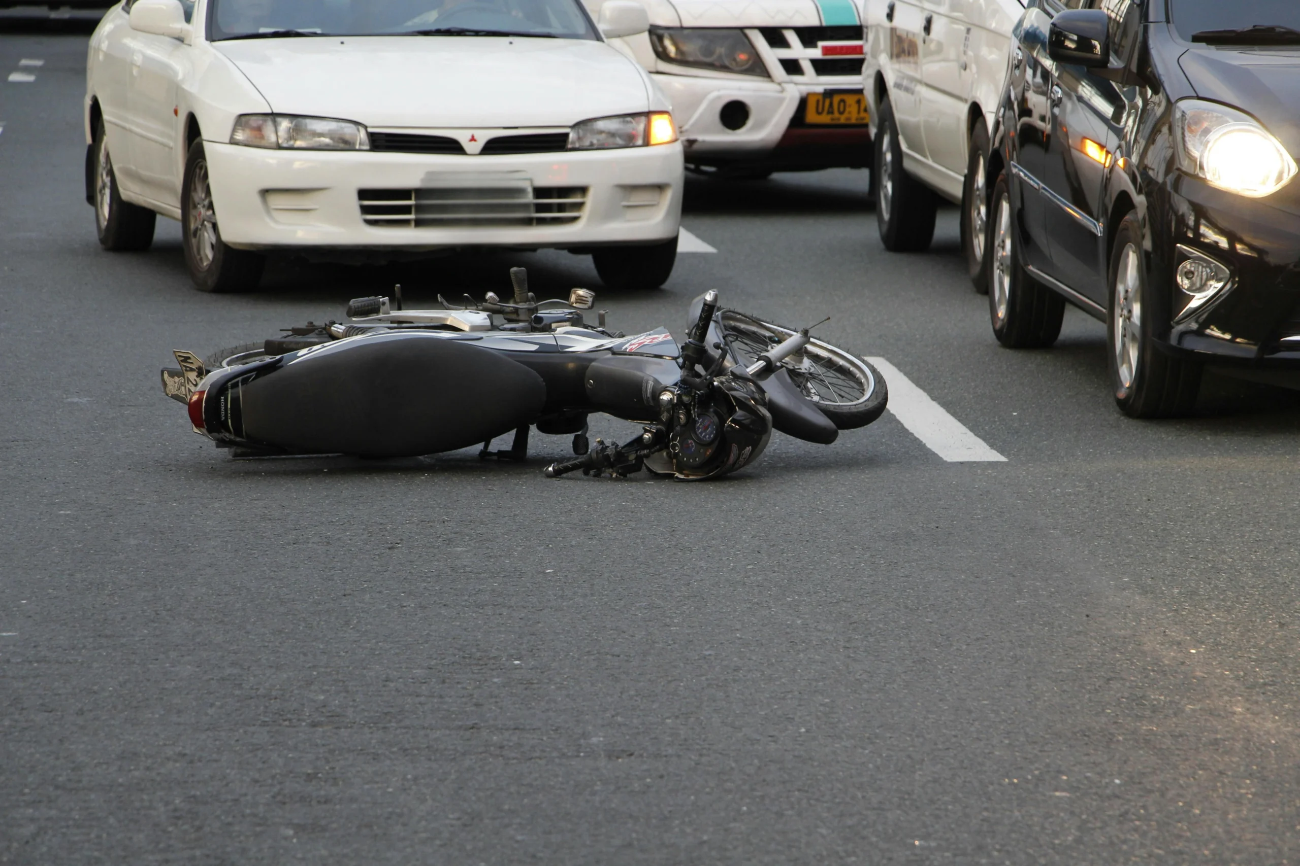 Motorcycle lying on road after traffic accident with cars